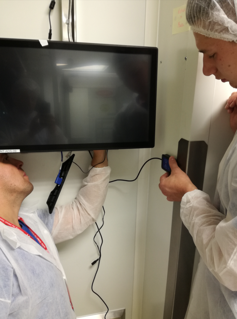 people installing screen on factory shop floor